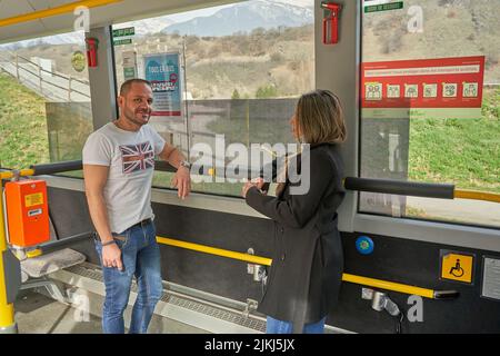 Zwei Fahrgäste stehen während der Fahrt in einem Bus und sprechen Stockfoto