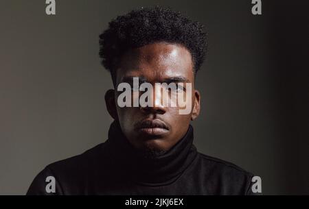 Das Porträt eines afroamerikanischen Mannes im dunklen Hintergrund. Stockfoto