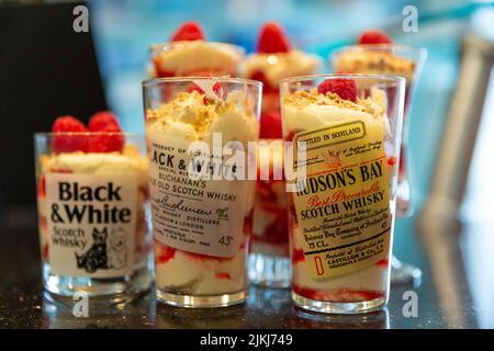 Whiskey-Shots in Gläsern mit schottischem Shortbread und Erdbeercreme-Desserts Stockfoto