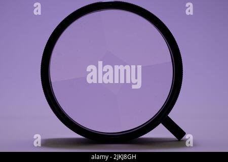 Eine Illustration einer schwarzen Lupe auf einem violetten Hintergrund Stockfoto