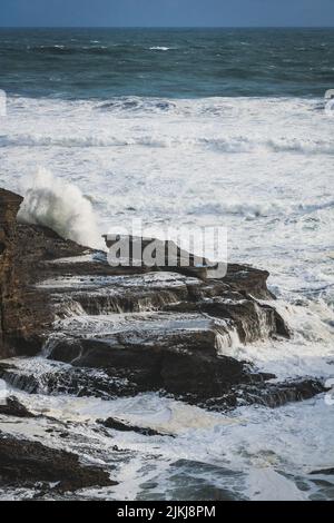 Eine wunderschöne Aussicht auf die Wellen, die auf die Felsformationen am Piha Beach, Auckland, Neuseeland, krachen Stockfoto