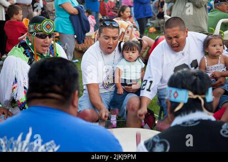 POW Wow Trommler halten Kinder fest, während sie ein traditionelles Lied im Shoshone Bannock Pow Wow, Fort Hall, Idaho, Trommeln Stockfoto