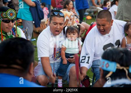 POW Wow Trommler halten Kinder fest, während sie ein traditionelles Lied im Shoshone Bannock Pow Wow, Fort Hall, Idaho, Trommeln Stockfoto