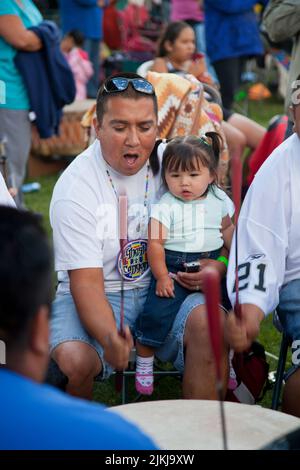 POW Wow Trommler halten Kinder fest, während sie ein traditionelles Lied im Shoshone Bannock Pow Wow, Fort Hall, Idaho, Trommeln Stockfoto