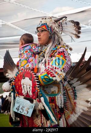 Die POW Wow-Tänzerin hält ihr Baby beim Tanzen im Shoshone Bannock Pow Wow, Fort Hall, Idaho Stockfoto