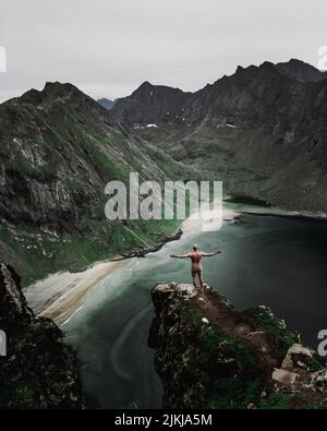 Eine Luftaufnahme eines Mannes, der am Rand einer Klippe mit Blick auf das Meer steht - Konzept der Freiheit Stockfoto