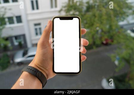 Eine Männerhand, die ein Smartphone wie ein iPhone X mit einem leeren Kopierraum im Freien hält Stockfoto