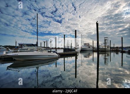 Im Hafen verankerte Boote mit Wolken, die sich im Wasser auf Hilton Head Island, South Carolina, USA, spiegeln Stockfoto