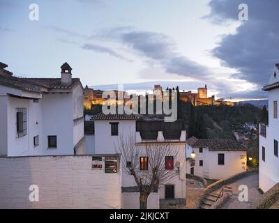 Eine Alhambra in Spanien in der Abenddämmerung mit weißen traditionellen Gebäuden im Vordergrund Stockfoto