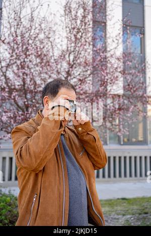 Älterer Mann genießt seine alte Filmkamera, die die Stadt fotografiert. Stockfoto