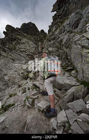 Eine Rückansicht eines männlichen Touristen mit Rucksack beim Wandern in der Hohen Tatra Stockfoto