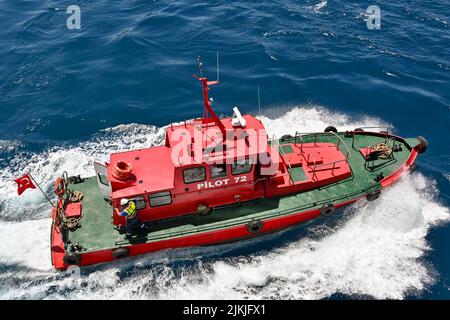 Kusadasi, Türkei - 2022. Mai: Luftaufnahme eines Lotsenbootes, das ein Kreuzschiff verlässt, nachdem es aus dem Hafen geführt wurde Stockfoto