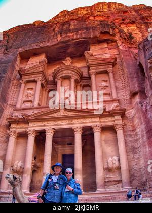 Eine vertikale Aufnahme einer Frau und eines Mannes, die gegen den Petra-Tempel stehen Stockfoto