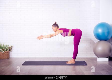 Ein Fitnesstrainer, der Yoga-Positionen in einem Studio vorführt Stockfoto