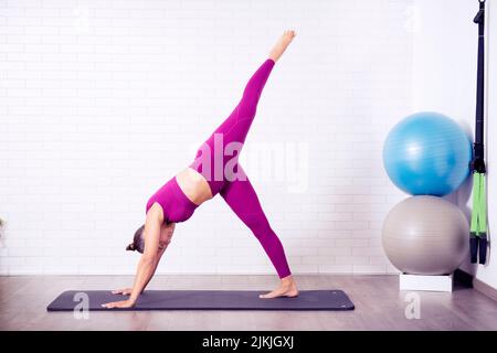 Ein Fitnesstrainer, der Yoga-Positionen in einem Studio vorführt Stockfoto