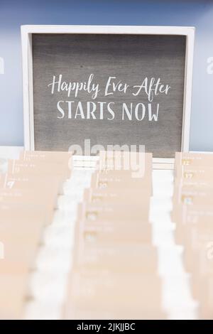 Eine vertikale Aufnahme einer Linie von Karten mit schwarzer Tafel mit dem Text „Happily Ever After STARTS NOW“ darauf Stockfoto
