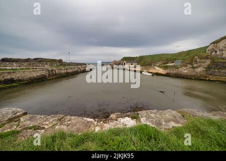 Eine wunderschöne Aufnahme des Hafens von Ballintoy unter stürmisch bewölktem Himmel in Ballintoy, Nordirland, Großbritannien Stockfoto