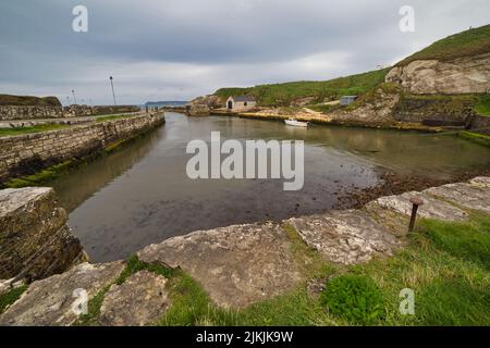 Eine wunderschöne Aufnahme des Hafens von Ballintoy unter stürmisch bewölktem Himmel in Ballintoy, Nordirland, Großbritannien Stockfoto