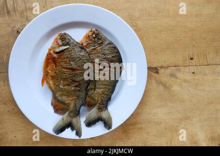 pomfret auf weißem Teller mit Holztisch Stockfoto