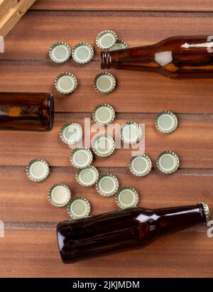 Eine vertikale Aufnahme von Glasflaschen auf einem Holztisch und verstreuten Dächern unter Flaschen Stockfoto