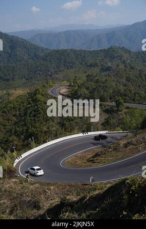 Eine vertikale Aufnahme von Autos, die tagsüber auf einer kurvenförmigen Autobahn fahren, umgeben von Bäumen. Stockfoto