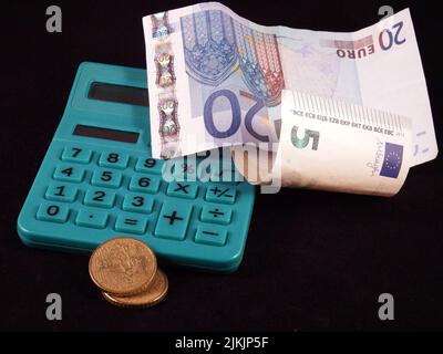 Ein Taschenrechner unter den Banknoten neben einigen Münzen. Stockfoto