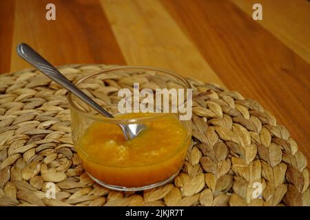 Orangenmarmelade in Glasbecher mit silbernem Löffel Stockfoto