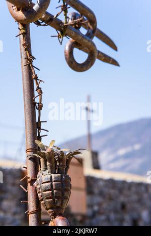 Eine vertikale Nahaufnahme des Metallmastes mit Stacheldraht und einer alten Granate. Weltkrieg 1, Norditalien. Stockfoto