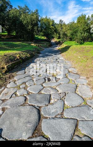 Eine alte gepflasterte Straße in der römischen Stadt Cumae im archäologischen Park Cumae, Pozzuoli, Italien Stockfoto