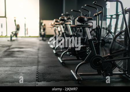 Fitnessgeräte. Stationäre Fahrräder stehen in einer Reihe im leeren Fitnessstudio Stockfoto