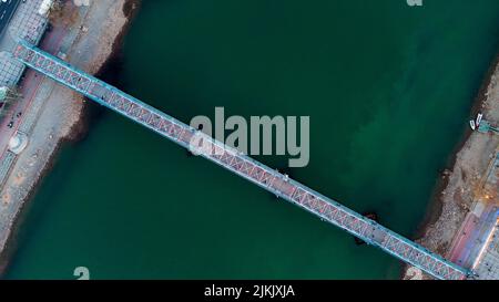 Eine Luftaufnahme einer blauen Brücke über den schmalen grünen Fluss Stockfoto