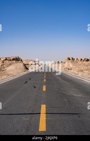 Eine vertikale Aufnahme einer leeren Autobahn inmitten von Klippen unter dem klaren Himmel Stockfoto