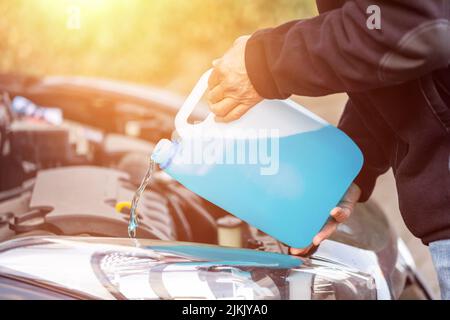 Mann füllt Scheibenwischerwasser auf einem Auto Stockfoto