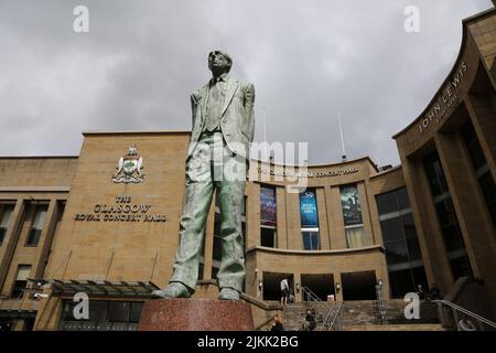 Glasgow, Schottland, Großbritannien. Statue des ersten Ministers Donald Dewar vor der Royal Concert Hall in Schottland.Glasgow, Buchanan Street.Statue von Donald Dewar am nördlichen Ende der Buchanan Street. Donald Dewar ein schottischer Politiker. Als Mitglied der Labour Party vertrat er Schottland 1966–1970 und dann ab 1978 im britischen Parlament. Bis zu seinem Tod 2000 war er Schottlands erster Minister. Seine Bronzestatue überblickt die Buchanan Street, eine der schönsten Durchgangsstraßen der Stadt, und steht auf den Stufen der Royal Concert Hall. Die Statue wurde am 7. Mai 2002 enthüllt. Stockfoto