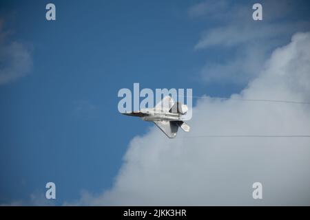Nahaufnahme eines Tarnflugzeugs Lockheed Martin F-22 Raptor, das mit Spuren am Himmel fliegt Stockfoto