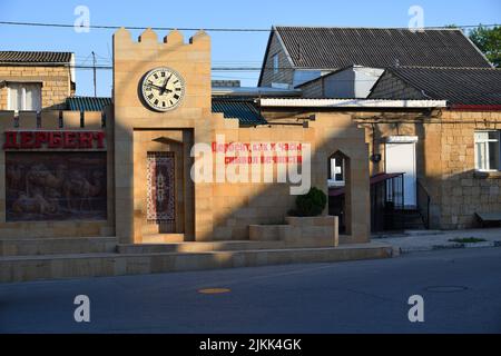 Derbent, Russland - 24. Juli 2022: Uhr an der Hausmauer in der Altstadt. Kyrillische Inschrift an der Wand bedeutet - Derbent, wie eine Uhr, ist ein Symbol für e Stockfoto