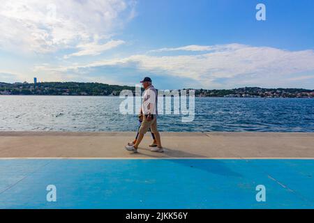 Das ältere Paar ging Hand in Hand am Strand am Meer. Istanbul, Türkei. Stockfoto