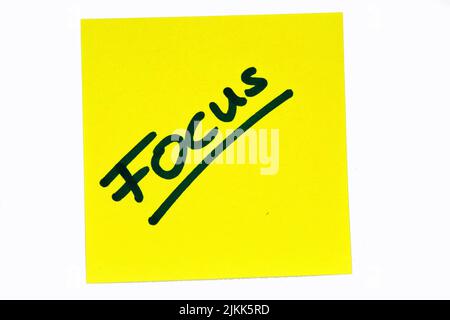 Ein inspirierendes, schwarzes Zitat mit dem Titel „Fokus“ auf einem gelben Post-it auf weißem Hintergrund Stockfoto