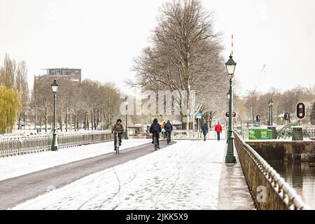 Menschen wandern und radeln über den schneebedeckten Sluice Gate Boulevard zwischen Lombok und Oog in Al-Stadtteilen Stockfoto