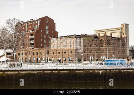 Ehemaliges Fabrikgebäude hinter dem Kai von Utrecht Leidsche Rijn Kanal Boulevard bedeckt mit Schnee mit Wohnturm daneben Stockfoto