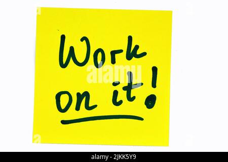 Ein schwarzes Motivationszitat mit der Aufschrift „Work on it!“ Auf einer gelben Note Stockfoto