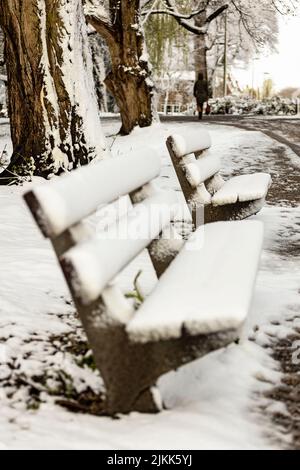 Bank in Oog im Al Park, bedeckt von dichtem Schneesack. Stockfoto