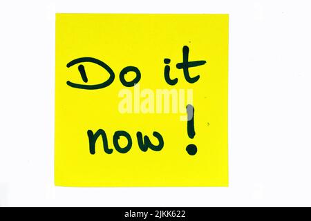 Ein schwarzes Motivationszitat mit der Aufschrift „Do it now!“ Auf einer gelben Note Stockfoto