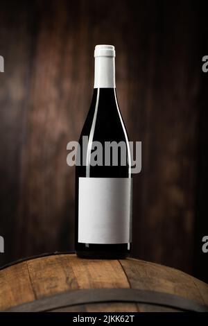 Eine Rotweinflasche auf Woddenfass mit einem hölzernen Backgorund aus der Nähe Stockfoto