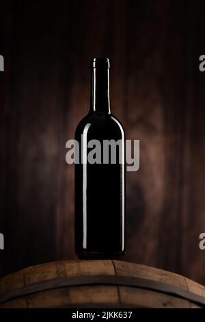 Eine Rotweinflasche auf Woddenfass mit einem hölzernen Backgorund aus der Nähe Stockfoto