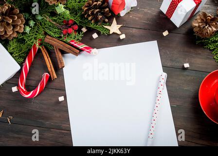 Draufsicht auf weihnachtsbrief in der Hand des weihnachtsmannes. Nahaufnahme der Hände mit leerer Wunschliste auf Holztisch mit Weihnachtsdekoration. High-Angle-Ansicht von SA Stockfoto