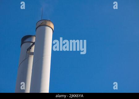 Kamine eines Holzpellet-Kraftwerks für die lokale Wärmeversorgung vor blauem Himmel Stockfoto