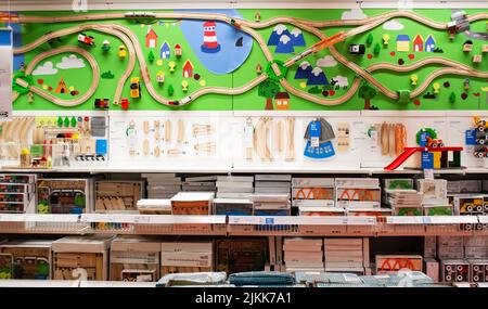 Moskau, Russland, Februar 2021: Die Spielwarenabteilung im Ikea-Geschäft. Hölzerne Kindereisenbahn mit Brücke, Kreisverkehr, Bäumen und Autos auf einer grünen BA Stockfoto
