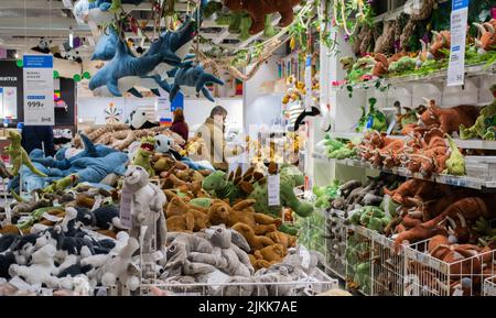 Moskau, Russland, Februar 2021: Ein Haufen weicher Spielzeuge in einem Ikea-Laden: Haie, Dinosaurier, Hasen, Hunde. Spielzeug auf Regalen, an der Decke Stockfoto