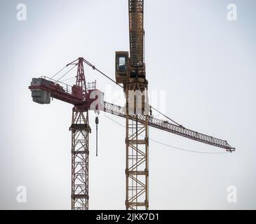 Zwei gelbe und rote Turmdrehkrane auf einer Baustelle gegen einen strahlenden Himmel Stockfoto